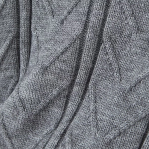 Macro shot of grey cable knit sweater texture showing detailed diamond stitch patterns