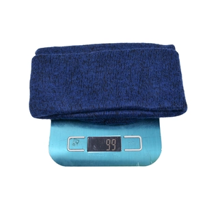 Close-up of a blue knitted winter hat weighing 99 grams on a digital scale