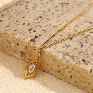 Detailed close-up of 18K gold plated rhombus pendant with a clear crystal on natural stone