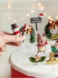 Close-up of a hand placing a Santa and reindeer topper on a festive Christmas cake