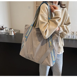 Gros plan d'un grand sac cabas gris en toile avec des bandoulières bleu et jaune
