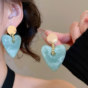 Detail of mint green heart earrings with marble texture and gold round studs