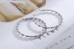 Macro shot of silver bamboo textured hoop earrings on a fashion magazine background