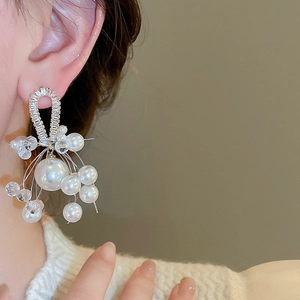 Detail of drop earrings with silver needles, faux pearls and crystals on a model