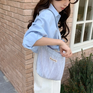 Dettaglio della borsa tote in velluto azzurro con etichetta tessuta mostrata sul modello