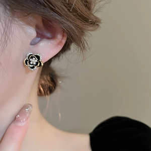 Boucles d'oreilles camélia vintage en noir et or avec perles portées par un mannequin