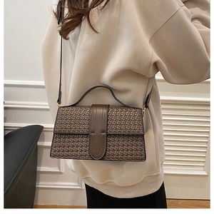 Brown woven texture handbag detail shown on model with shoulder strap and retro design