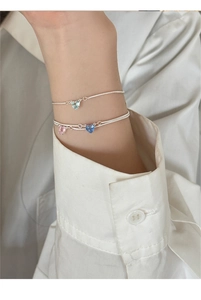 Dettaglio di un bracciale in argento 925 con ciondoli a cuore in zircone colorato al polso
