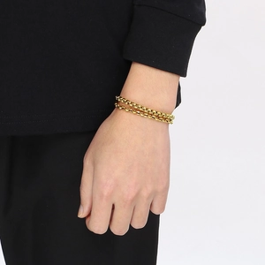 Dettaglio di un bracciale a doppia catena a scatola dorata indossato da un modello