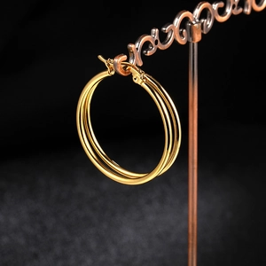 Close-up of triple layered gold hoop earrings displayed on a vintage metal stand