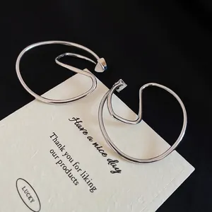 Minimalist silver wavy clip-on earrings displayed on a textured beige card