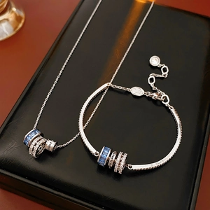 Detail of silver necklace set featuring blue gems and Love is All engraving