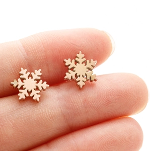 Minimalist 18K gold plated stainless steel snowflake stud earrings shown on fingertip