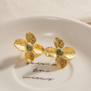 Vintage gold flower stud earrings with green turquoise inlay on a ceramic plate