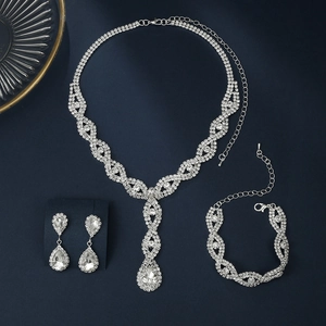 Elegant silver-colored crystal jewelry set including necklace and drop earrings on blue velvet