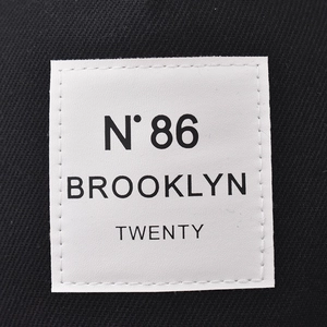 Detail van het N° 86 Brooklyn borduursel en wit label op de zwarte katoenen pet