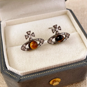 Détail macro des boucles d'oreilles Saturne en oeil de tigre avec zircons et métal foncé