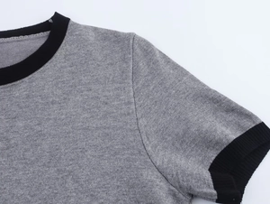 Detail van het grijze gebreide shirt met zwarte ronde hals en fijne stofstructuur