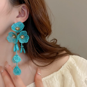 Macro shot of turquoise flower tassel earrings with zircons on an elegant female model