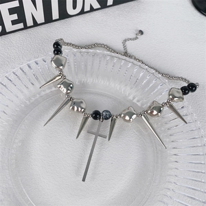 Dettaglio della collana punk con borchie metalliche e pendente a croce su piatto di vetro