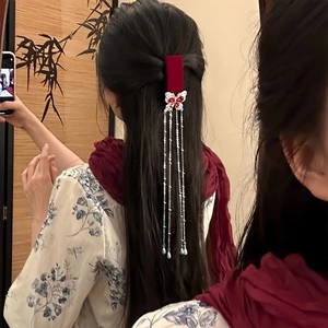 Detail of red velvet butterfly hair clip with long silver tassels on black hair