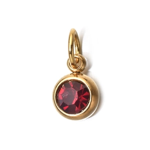 Detail shot of a 6mm golden round pendant with a single red gemstone for DIY jewelry