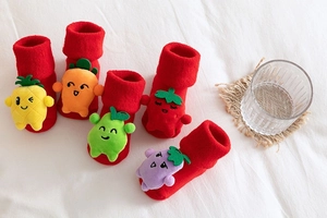 Detail of red baby Christmas socks with plush fruit decorations like pineapple and strawberry