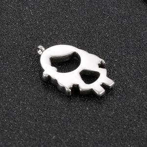 Close-up of a silver skull pendant with hollow eyes on a textured black background