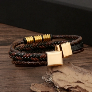 Detail of multi-layer braided leather bracelet with golden metal clasps on rustic wood