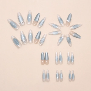 Detail of almond shaped press-on nails with blue cat-eye finish and 3D floral accents