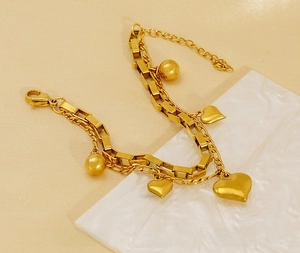 Détail d'un bracelet doré double couche avec charms cœurs et maillons en acier