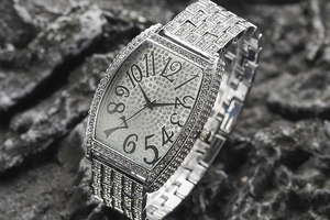 Macro view of tonneau-shaped silver watch with crystals and large Arabic numerals