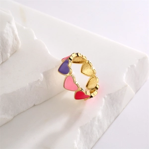 Detail of gold enamel ring with colorful heart patterns on a white textured stone base