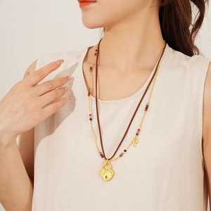 Detail of a brown double-layer leather necklace with a gold heart lock pendant and beads