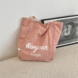 Pink canvas tote bag detail showing orange plaid lining and Bonjour magic print