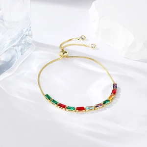 Detail of adjustable gold bracelet featuring a colorful rainbow baguette zircon row