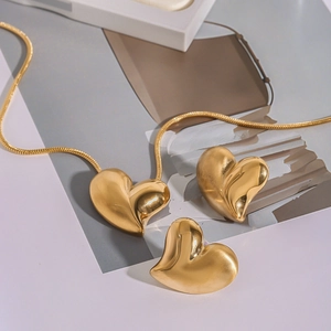 Detailed view of polished golden heart necklace and stud earrings set on artistic card
