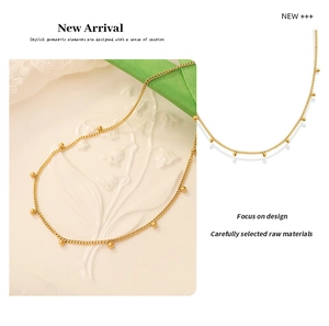 Detail view of a gold beaded choker necklace on a white embossed plate and lace