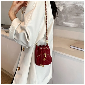 Detail of red quilted mini bucket bag with gold chain strap and camellia ornament