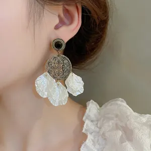 Boucles d'oreilles vintage avec pierres noires et pétales de coquillages sur modèle