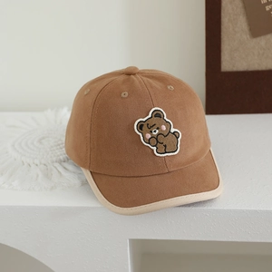 Close-up of cute bear embroidery and cream piping on a brown cotton baseball cap