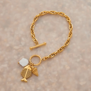Détail de breloques coquillages dorées et arêtes de poisson sur bracelet en acier