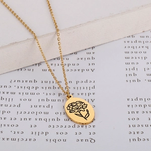 Macro shot of gold oval pendant with delicate carnation flower engraving on a thin chain