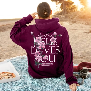 Purple hooded sweatshirt featuring cherry blossom print and Jesus Loves You quote on beach