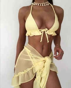 Dettaglio del bikini giallo con volant, gonna in mesh trasparente e collana di conchiglie