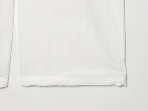 Gros plan détaillé du pantalon en nylon blanc montrant la texture du tissu et les coutures