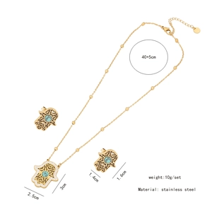 Detail view of gold Hamsa hand necklace set with turquoise stone and crystal inlay