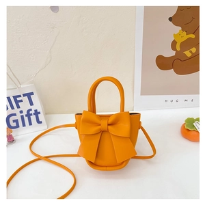 Detail of an orange mini bow crossbody bag with a round body and top handle