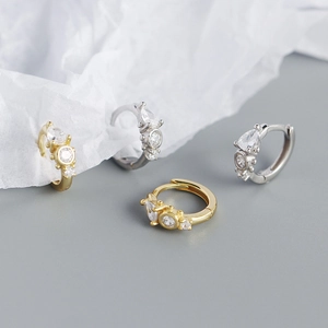 Detail of gold and silver S925 earrings with teardrop zircon crystals on white paper