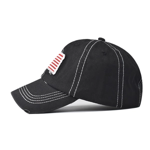 Detail of black cotton baseball cap with white contrast stitching and flag patch
